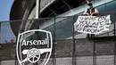 Seorang penggemar Arsenal membentangkan spanduk anti Liga Super Eropa di luar Stadion Emirates, London, Senin (19/4/2021). (Foto: AFP/Tolga Akmen)