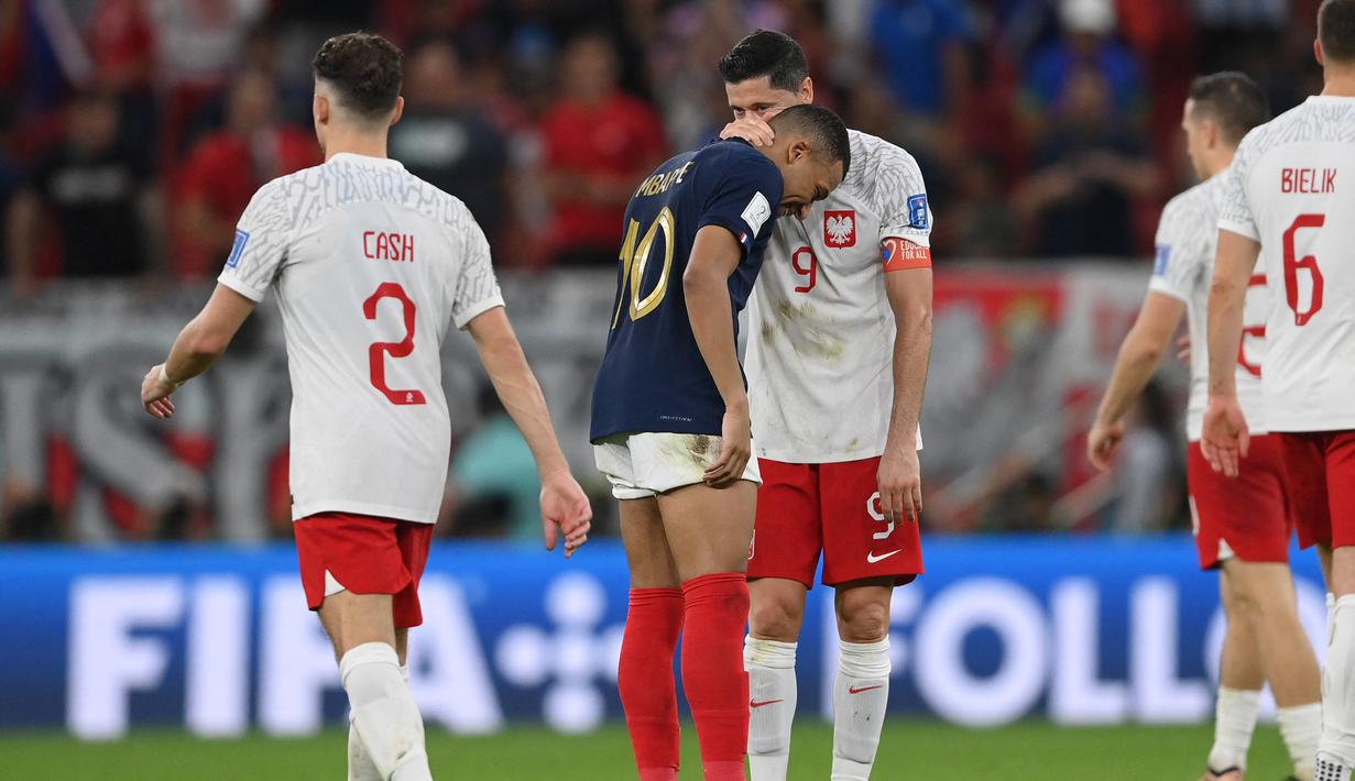 Usai laga, pemain bintang sekaligus kapten Polandia Robert Lewandowski yang berhasil menyumbang satu gol melalui eksekusi penalti kembali kedapatan berbisik dengan bintang tim rival, striker Prancis Kylian Mbappe. (AFP/Franck Fife)