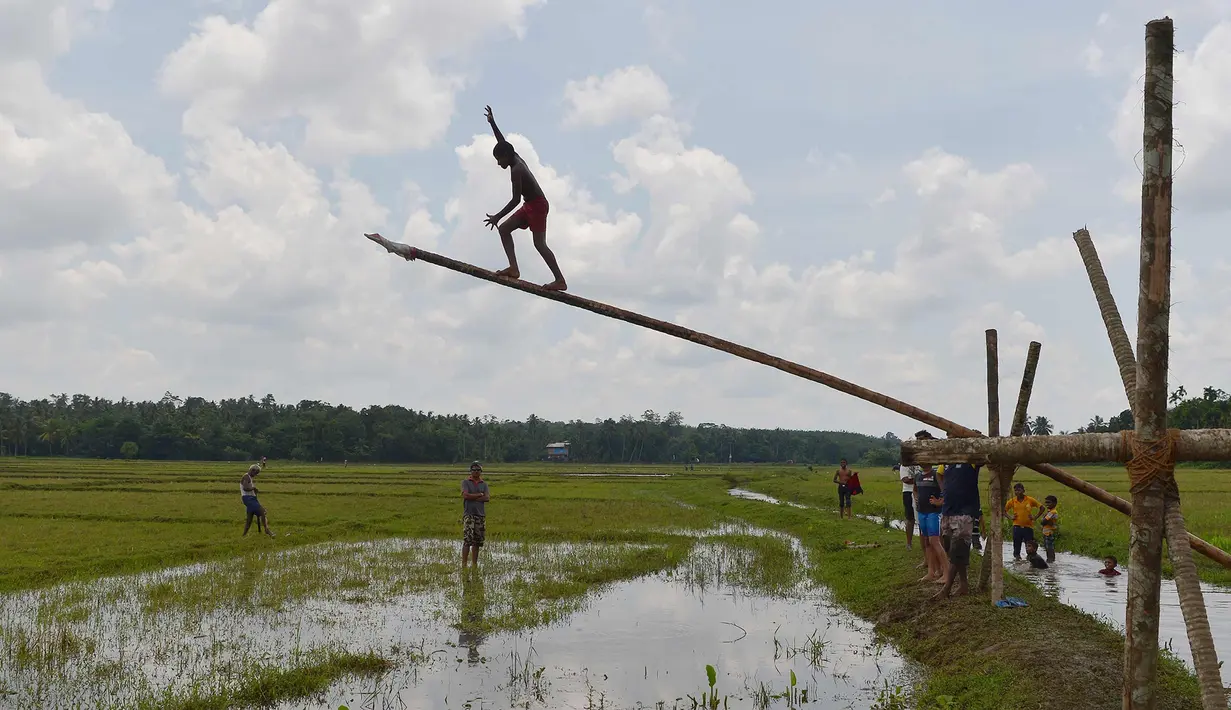 Pemuda Sri Lanka berusaha memanjat batang pohon selama perayaan Tahun Baru Sinhala dan Tamil di Bandaragama, Kolombo (21/4). Sejumlah perlombaan diadakan saat tahun baru umat Hindu, Sinhala dan Tamil yang jatuh 14 April. (AFP Photo/Lakruwan Wannirachchi)