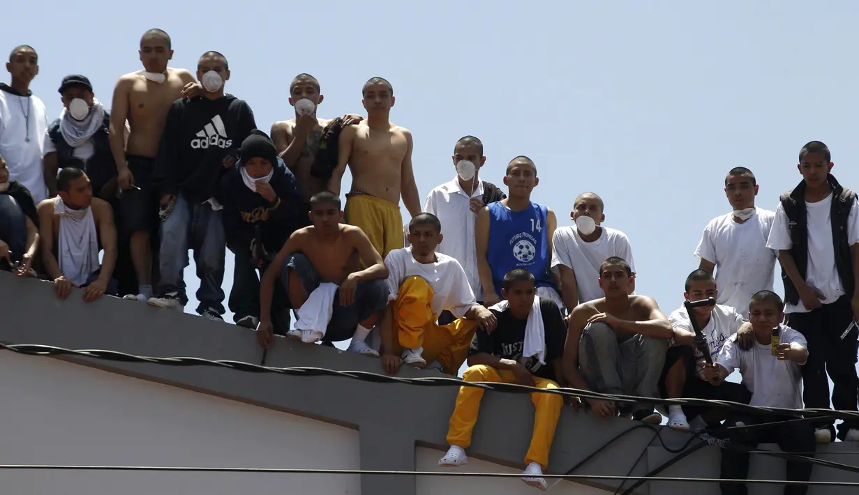 Sekelompok narapidana remaja berdiri diatap saat kerushuan di penjara Juvenile Gaviotas di Guatemala City, Guatemala (3/7). Kerusuhan di penjara tersebut terjadi usai dua narapidana ditemukan tewas tergantung. (AP Photo / Moises Castillo)