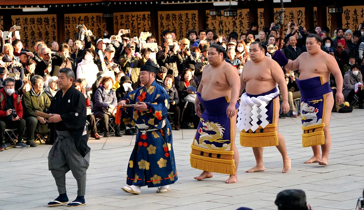Juara Grand Sumo asal Mongolia, Kakuryu (kanan) tiba untuk melakukan upacara mengentakkan kaki menyambut tahun baru di Kuil Meiji Shrine, Tokyo, Selasa (9/1). Ritual penyambutan tahun baru itu melibatkan tiga juara pegulat sumo. (AP/Shizuo Kambayashi)