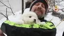 Seorang petugas pemadam kebakaran Italia menggendong anak anjing yang berhasil diselamatkan dari reruntuhan Hotel Rigopiano di Farindola, Italia (23/1). (Fabio Gatto / Vigili Del Fuoco / AFP)