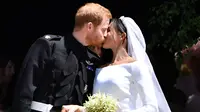 Pangeran Harry mencium istrinya, Meghan Markle di tangga Pintu Barat St George's Chapel, Kastil Windsor, Inggris, Sabtu (19/5). Pangeran Harry dan Meghan Markle telah resmi menikah. (Ben STANSALL/POOL/AFP)