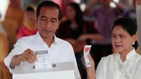 Calon Presiden Nomor Urut 01 Joko Widodo atau Jokowi dan istrinya, Iriana memasukkan surat suara ke dalam kotak suara saat melakukan pencoblosan dalam Pemilu 2019 di TPS 008 Gambir, Jakarta Pusat, Rabu (17/4). Jokowi dan Iriana terdaftar di nomor urut 154 dan 155 daftar DPT. (AP/Dita Alangkara)