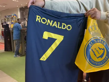 Kepastian bergabungnya Cristiano Ronaldo pada 31 Desember 2022 bersama klub papan atas Arab Saudi, Al Nassr langsung berpengaruh signifikan dari sisi bisnis. Para fans Al Aalami, julukan bagi Al Nassr, berbondong-bondong mengunjungi toko resmi pernak-pernik klub Al Nassr di Riyadh untuk berburu jersey bernomor punggung 7 bertuliskan "Ronaldo". (AFP/Fayez Nureldine)
