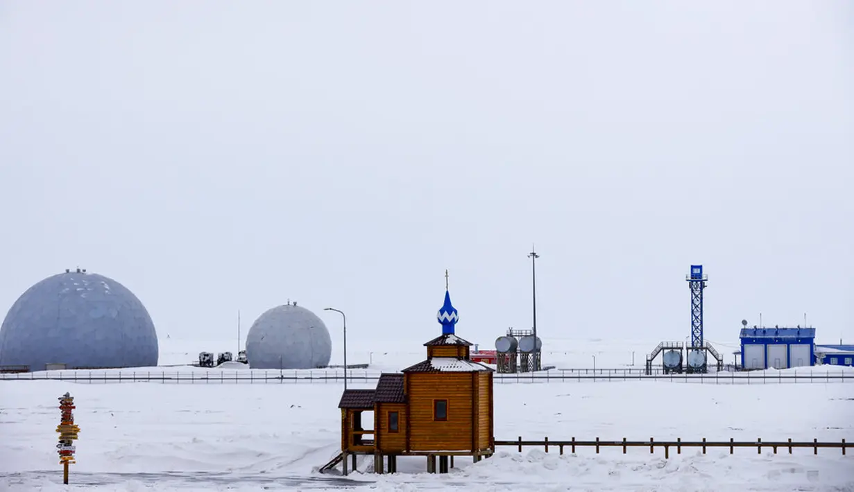 Sebuah Gereja Ortodoks terlihat dengan fasilitas radar pada latar belakang Pulau Alexandra Land dekat Nagurskoye, Rusia, Senin (17/5/2021). Tempat yang dulunya merupakan rumah terpencil bagi beruang kutub ini kini menjadi pangkalan militer paling utara Rusia. (AP Photo/Alexander Zemlianichenko)