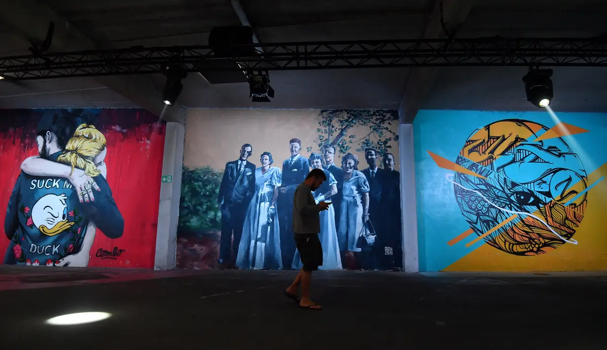 Seorang pria berjalan di dekat kreasi seni jalanan yang ditampilkan sebagai bagian dari pameran "Strokar inside" pada malam pembukaan acara di bekas supermarket di Brussels (5/9). (AFP Photo/Emmanuel Dunand)