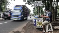 Feri (28) saat menyelesaikan jasa servis kartu tanda penduduk (KTP) di Jakarta, Kamis (21/1/2021). Bermodal meja lipat, poster, dan peralatan pendukung seperti lem, korek api, serta plastik laminating, Feri membuka jasa servis kartu identitas di pinggir jalan Ibu Kota. (merdeka.com/Iqbal S. Nugroho)