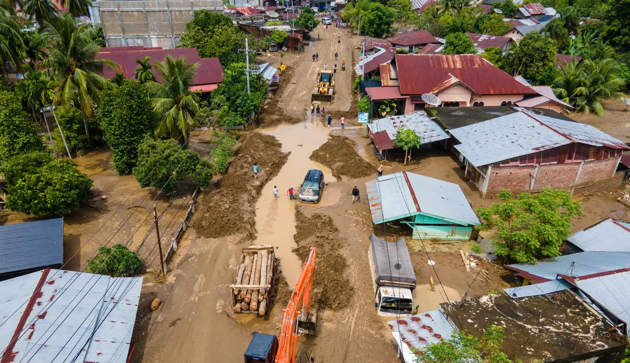 Badan Penanggulangan Bencana Daerah (BPBD) Pidie Jaya bersama tim SAR gabungan masih melakukan pendataan serta upaya evakuasi warga yang terjebak banjir. Petugas juga berusaha membuka jalur alternatif terkait jembatan nasional yang rusak. Tampak foto udara menunjukkan sebuah ekskavator sedang membersihkan lumpur dari banjir bandang di jalan utama yang menghubungkan Aceh dan Sumatera Utara di Meureudu, Kabupaten Pidie Jaya, Provinsi Aceh, pada Jumat 28 November 2025. (CHAIDEER MAHYUDDIN/AFP)