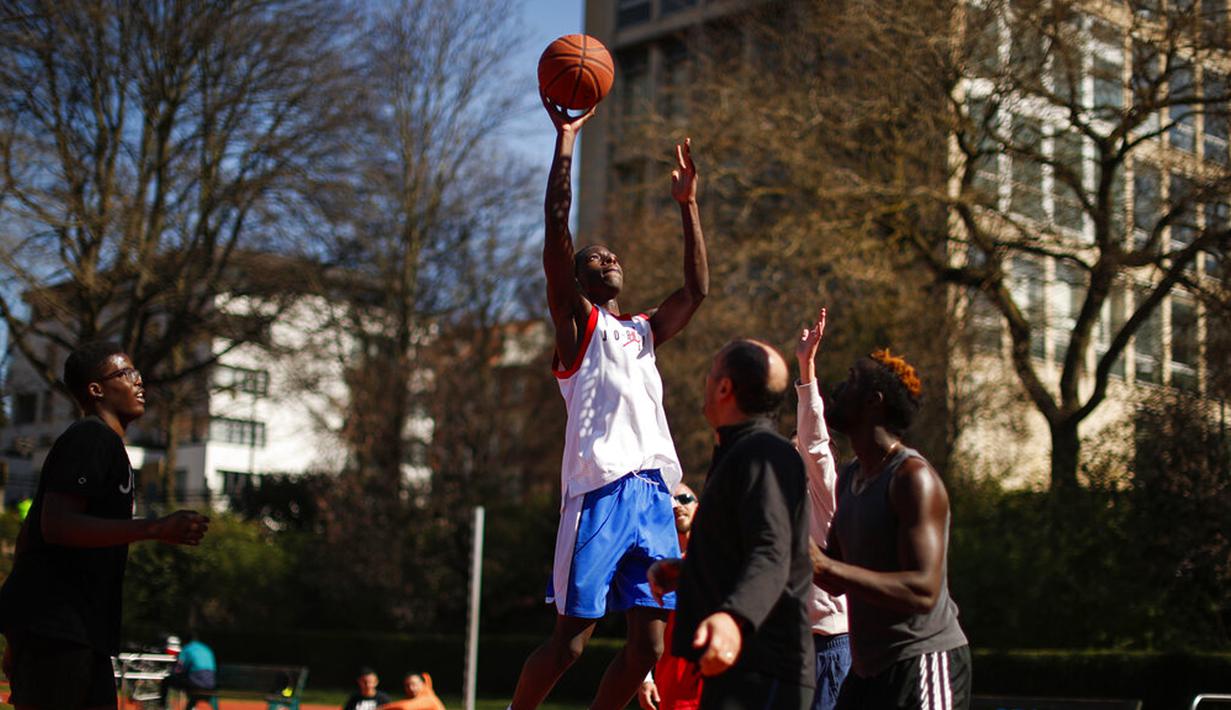 Orang-orang bermain bola basket di Taman Cinquantenaire, Brussel, Belgia, Senin (29/3/2021). Belgia kembali memberlakukan lockdown ketat sebagai tanggapan atas lonjakan infeksi COVID-19 yang mengkhawatirkan. (AP Photo/Francisco Seco)