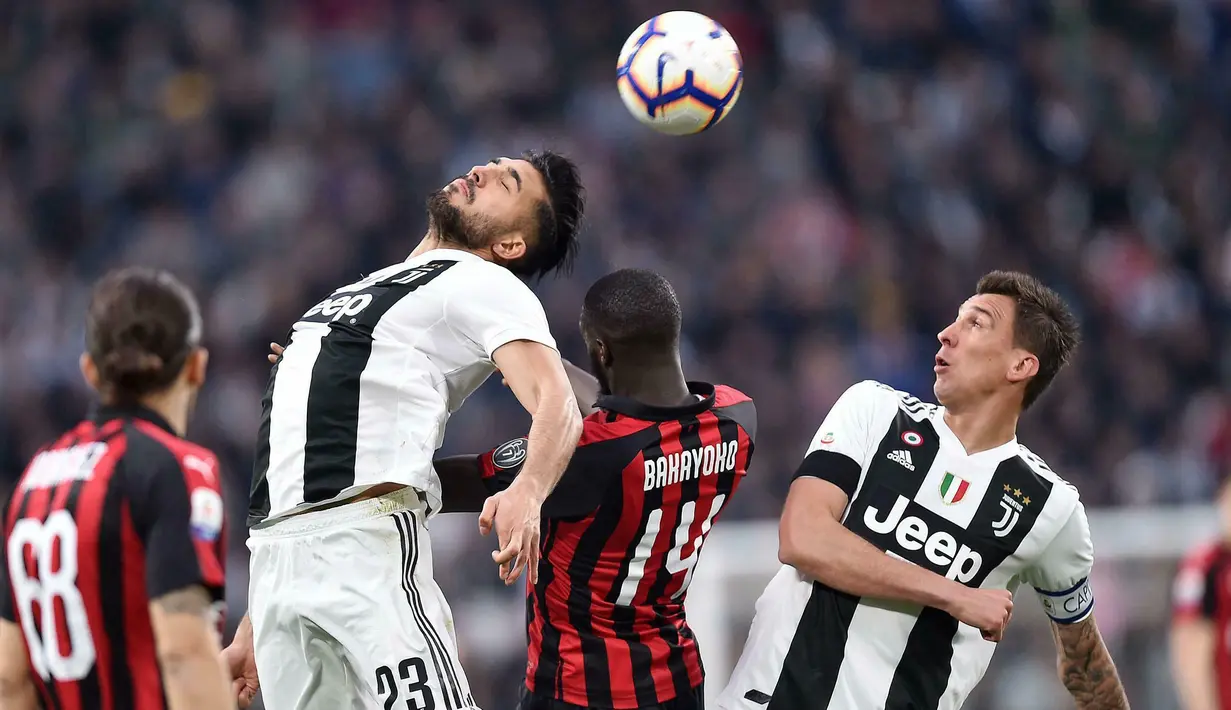 Gelandang Juventus, Emre Can, duel udara dengan gelandang AC Milan, Tiemoue Bakayoko, pada laga Serie A di Stadion Allianz, Turin, Sabtu (6/4). Juventus menang 2-1 atas AC Milan. (AP/Andrea Di Marco)