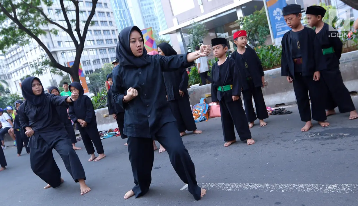 Sejumlah pendekar perempuan memperagakan jurus beladiri di hadapan warga saat Car Free Day di kawasan Senayan, Jakarta, Minggu (8/10). Aksi ini untuk melestarikan olahraga pencak silat Betawi. (Liputan6.com/Fery Pradolo)
