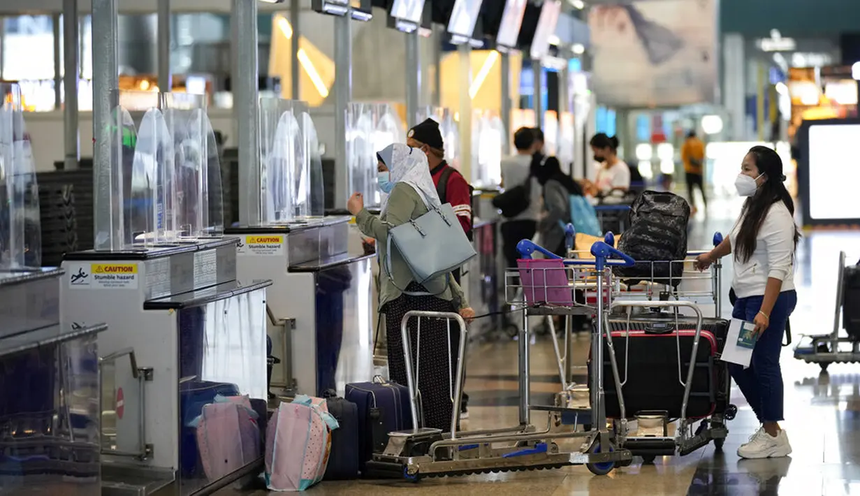 Pelancong mengantre di konter check-in Bandara Internasional Kuala Lumpur, Sepang, Malaysia, Jumat (1/4/2022). Mulai hari ini, Malaysia membuka perbatasannya untuk orang asing dan pelancong yang sudah divaksin COVID-19 lengkap tanpa harus menjalani karantina. (AP Photo/Vincent Thian)