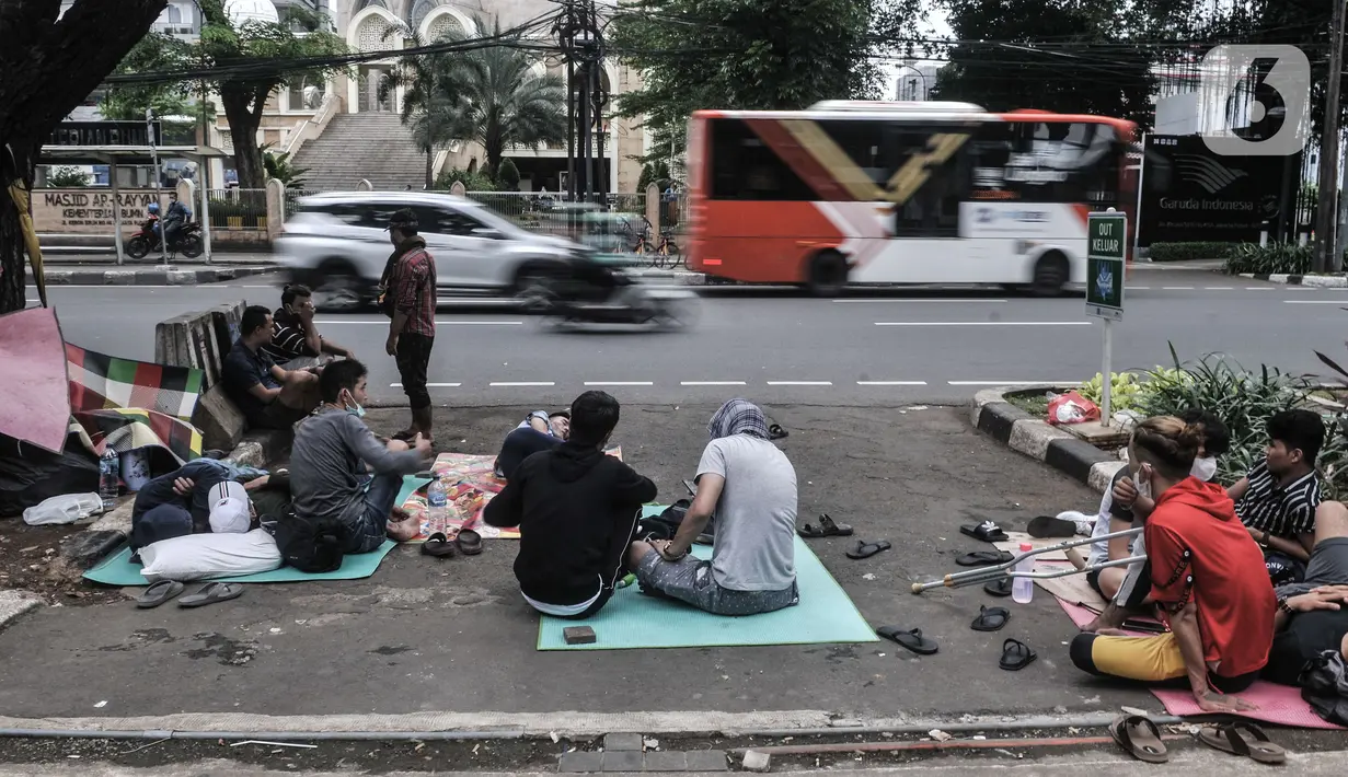 Kendaraan melintas di dekat imigran pencari suaka yang menghuni di depan Kantor UNHCR Kebon Sirih, Jakarta, Kamis (1/4/2021). Puluhan imigran dari berbagai negara konflik kembali menghuni di depan Kantor UNHCR Kebon Sirih sejak beberapa waktu lalu. (merdeka.com/Iqbal S Nugroho)