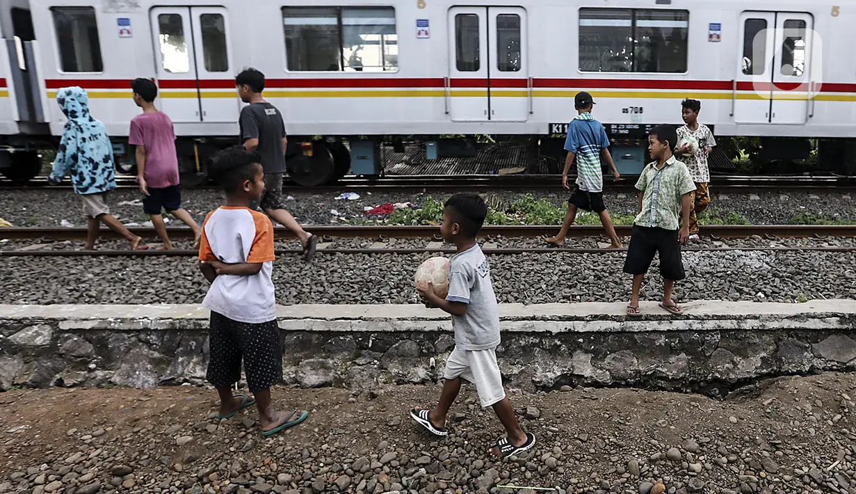 Anak-anak bermain bola di tengah perlintasan kereta api kawasan Ancol, Jakarta Utara, Kamis (19/5/2022). Dari 14 kasus dugaan hepatitis akut terdapat 6 kasus meninggal dunia, 4 kasus masih dirawat, dan 4 kasus sudah dipulangkan. (Liputan6.com/Johan Tallo)