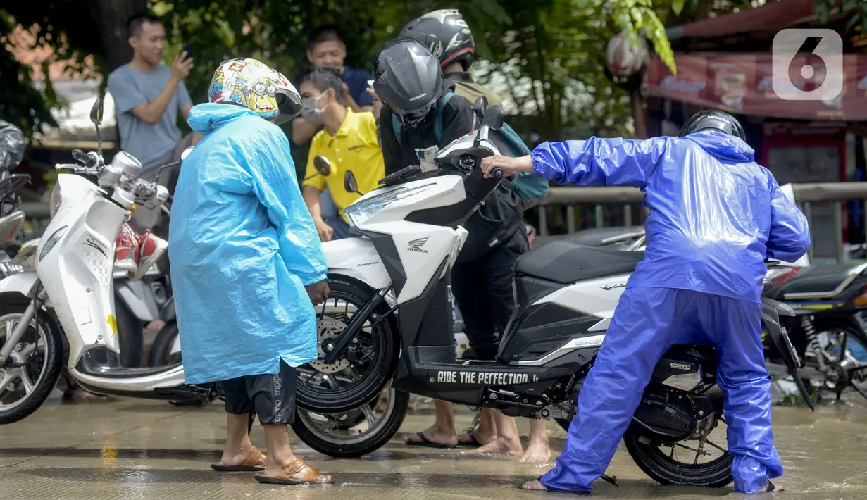 Pengendara motor membuang air yang masuk ke dalam knalpot saat melintasi banjir di Jalan Husein Nastranegara Perapatan Rawa Bokor, Tangerang, Sabtu (1/2/2020). Hujan deras yang mengguyur sejak Jumat (31/1) malam menyebabkan sejumlah kawasan di Tangerang terandam air. (merdeka.com/Imam Buhori)