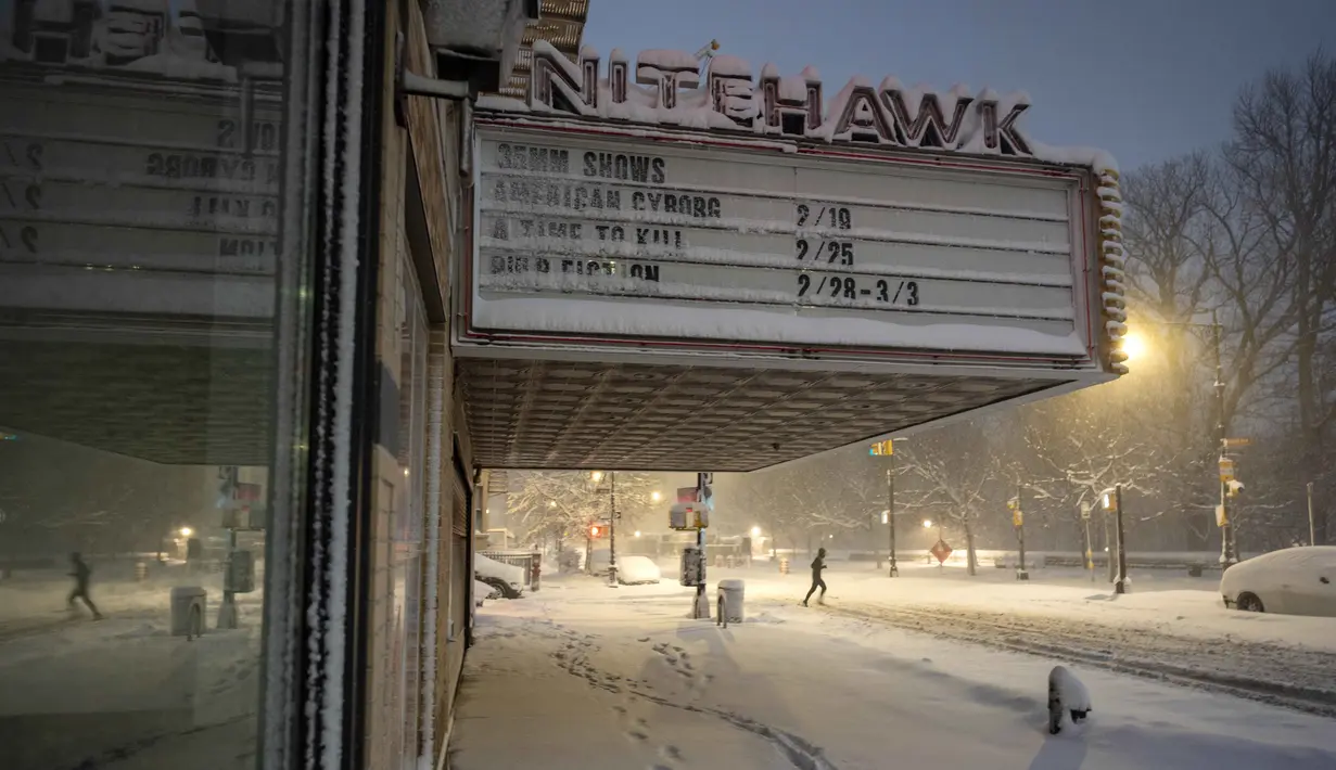 Badan Layanan Cuaca Nasional (NWS) melaporkan intensitas salju yang turun sangat ekstrem, mencapai lima hingga tujuh sentimeter per jam. Tampak dalam foto, seorang pelari berlari melewati Nitehawk Cinema di distrik Brooklyn, Kota New York, sebelum matahari terbit pada Senin 23 Februari 2026. (Jeremy Weine/Getty Images North America/Getty Images via AFP)