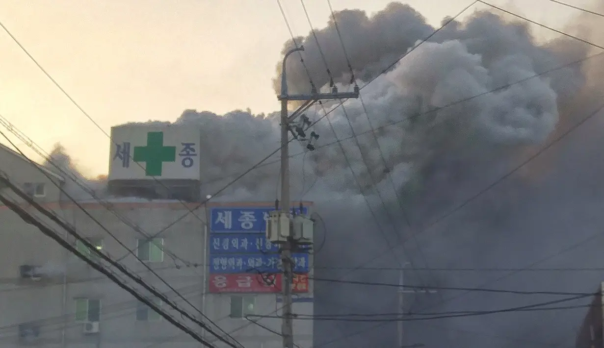 Kepulan asap membumbung tinggi saat petugas pemadam kebakaran berusaha memadamkan api yang membakar rumah sakit Sejong di Milyang, Korea Selatan, Jumat (26/1). Sekitar 200 orang berada di gedung Rumah Sakit saat kebakaran tersebut. (YONHAP / AFP)