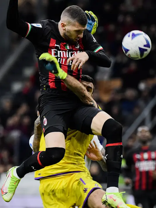 Penyerang AC Milan Ante Rebic (Atas) bertabrakan dengan kiper Fiorentina Pietro Terracciano pada duel pekan ke-15 Serie A 2022/2023 di San Siro, Senin (14/11/2022). Kemenangan itu membuat AC Milan masih menduduki peringkat dua klasemen dengan koleksi 33 poin dari 15 pertandingan. (Filippo MONTEFORTE / AFP)