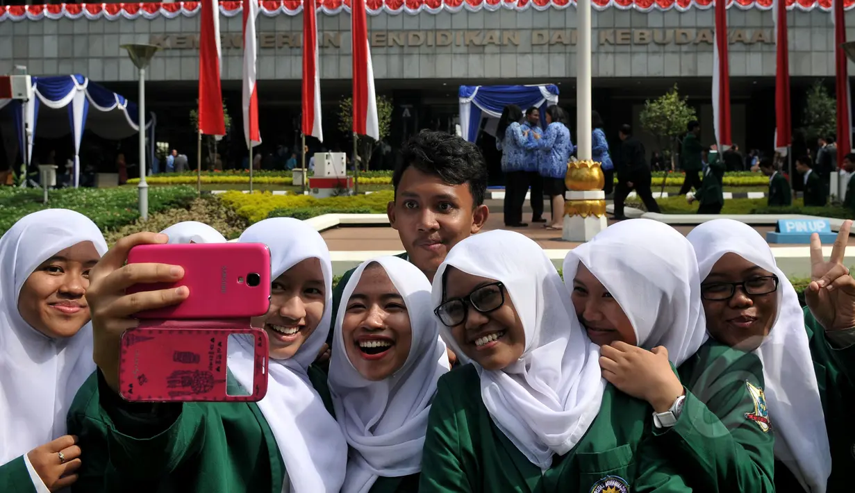 Sejumlah pelajar ber-selfi seusai mengikuti upacara memperingati Hari Pendidikan Nasional di Jakarta, Sabtu (2/5/2015). Peringatan tersebut mengangkat tema 'Gerakan Pencerdasan dan Penumbuhan Generasi Berkarakter Pancasila'. (Liputan6.com/Johan Tallo)