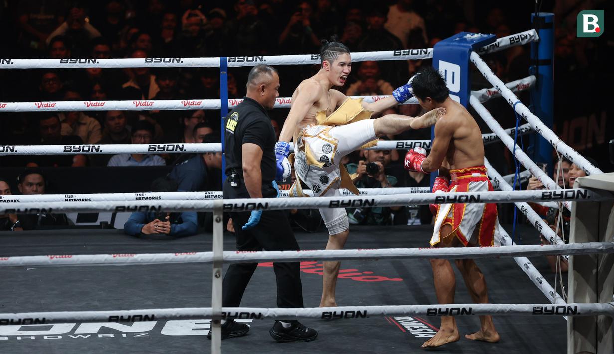 Petarung Malaysia, Ammarul Shafiq, melepaskan tendangan keras ke bagian rahang kiri petarung Indonesia, Serieal Effendy pada pertandingan Byon Combat Showbiz Vol. 6 di Tennis Indoor Senayan, Jakarta, Sabtu (22/10/2025). (Bola.com/M Iqbal Ichsan)