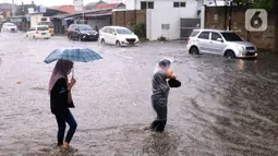 Warga melintasi banjir di jalan Bayangkara Pusdiklat, Kota Tangerang Selatan, Banten, Selasa (2/11/2021). BMKG mengeluarkan peringatan potensi cuaca ekstrem di wilayah Jakarta, Bogor, Depok, Tangerang, dan Bekasi (Jabodetabek). (Liputan6.com/Angga Yuniar)