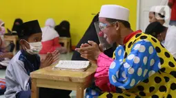 Yahya Edward menggunakan kostum badut bertepuk tangan sangat mengajar di Pinang, Kota Tangerang, Banten, Kamis (29/4/2021). Mengajar ngaji menggunakan kostum badut tersebut untuk memotivasi anak-anak agar tetap semangat belajar sekaligus untuk menghibur anak didiknya. (Liputan6.com/Angga Yuniar)