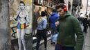 Sejumlah warga melintasi mural dengan gambar bintang Juventus, Cristiano Ronaldo, yang terdapat di Milan, Senin (19/3). Mural berjudul Cristiano's Secret ini karya seniman Italia, TvBoy. (AFP/Miguel Medina)