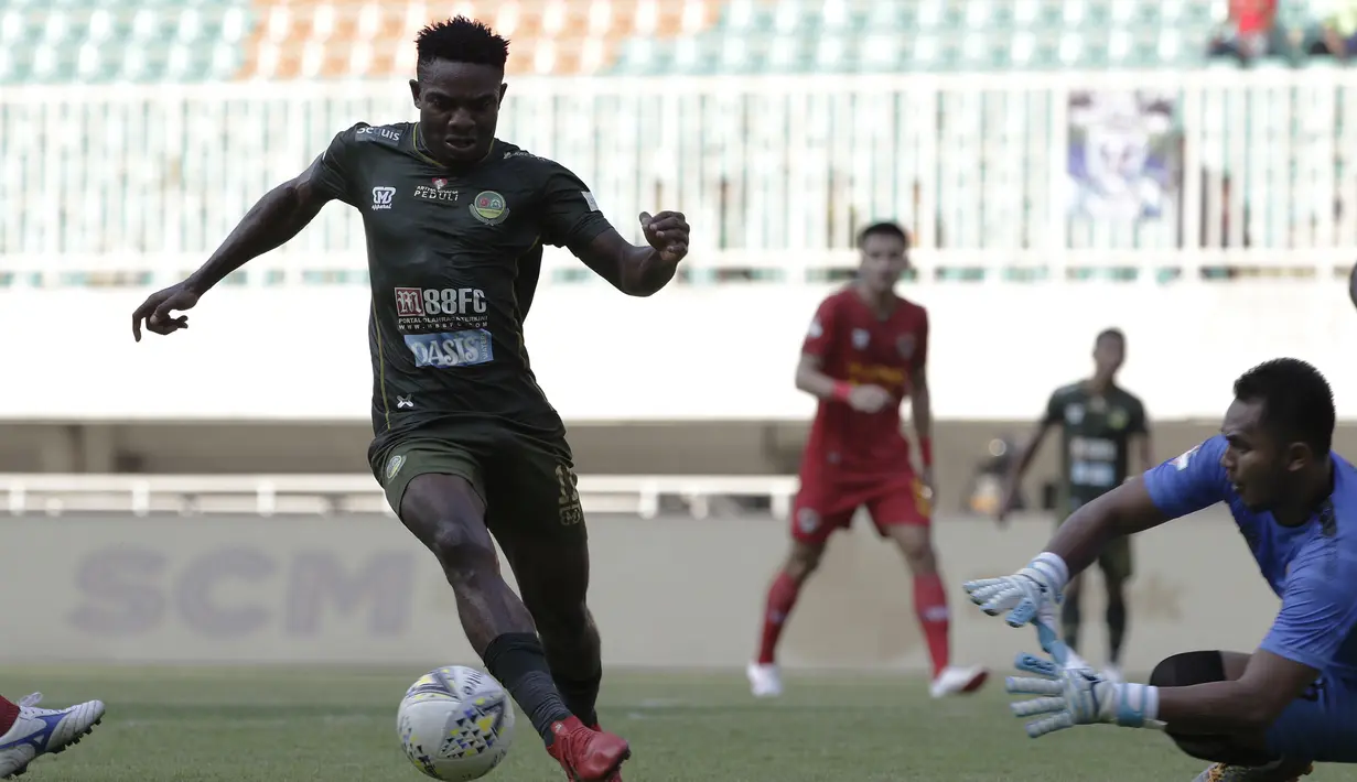 Gelandang Tira Persikabo, Osas Saha, berusaha melewati kiper Kalteng Putra, Dimas Galih, pada laga Shopee Liga 1 di Stadion Pakansari, Bogor, Jumat (26/7). Tira Persikabo menang 5-2 atas Kalteng. (Bola.com/Yoppy Renato)