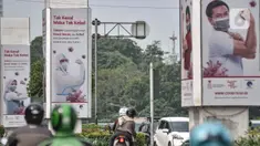 Kendaraan melintas di dekat papan reklame sosialisasi vaksin Covid-19 di tiang pancang proyek monorel, Senayan, Jakarta, Selasa (17/11/2020). Tiang pancang monorel yang terbengkalai selama 16 tahun itu dimanfaatkan oleh sebagai papan reklame sosialisasi vaksin Covid-19. (merdeka.com/Iqbal S Nugroho)