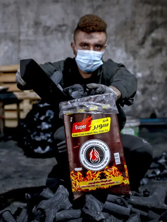 Seorang pekerja mengisi kantong arang di fasilitas produksi arang al-Hattab, sebelah timur Kota Gaza, Palestina, 28 Januari 2021. Fasilitas tersebut menghasilkan 80 hingga 90 ton arang per tahun. (Mohammed ABED/AFP)