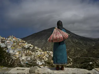 Foto yang diambil pada 6 Mei 2023 ini menunjukkan patung yang didedikasikan untuk perempuan Olympos, menghadap ke desa terpencil di pulau Karpathos. Di utara pulau Karpathos Yunani, desa lereng bukit Olympos adalah rumah bagi salah satu dari sedikit masyarakat matriarkal di Yunani yang menolak standardisasi pariwisata dan gaya hidup. (Louisa GOULIAMAKI / AFP)