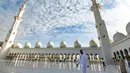 Seorang pria berjalan melewati halaman Masjid Agung Sheikh Zayed di Abu Dhabi, Uni Emirat Arab. Masjid ini adalah masjid terbesar ketiga di dunia setelah masjid di Mekkah dan Madinnah. (Photo by Vincenzo PINTO / AFP)