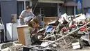 Warga membuang puing-puing usai banjir menerjang  Soja, Prefektur Okayama, Jepang, Senin (9/7). (Takaki Yajima/Kyodo News via AP)