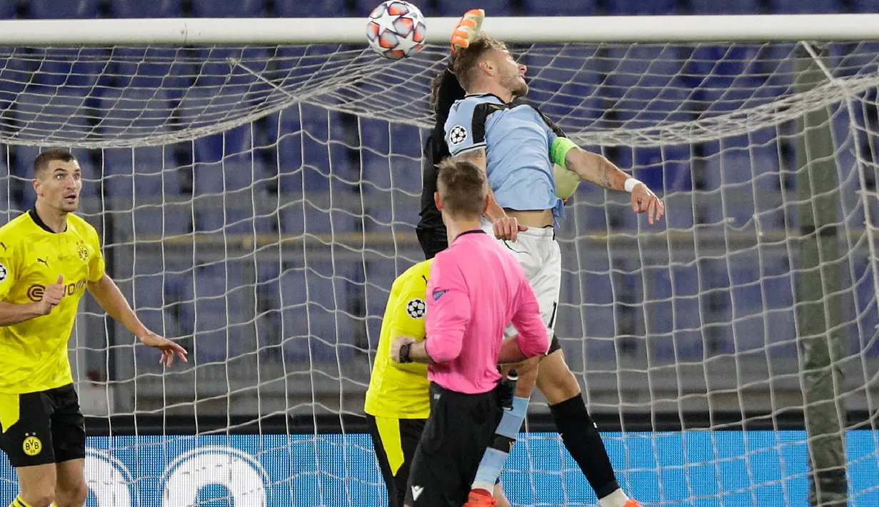 Kiper Borussia Dortmund, Marwin Hitz melompat saat berebut bola dengan penyerang andalan Lazio, Ciro Immobile pada pertandingan perdana Grup F Liga Champions 2020 di Stadion Olimpico, Rabu (21/10/2020) dini hari WIB. Lazio menang 3-1 atas Borussia Dortmund. (AP Photo/Gregorio Borgia)