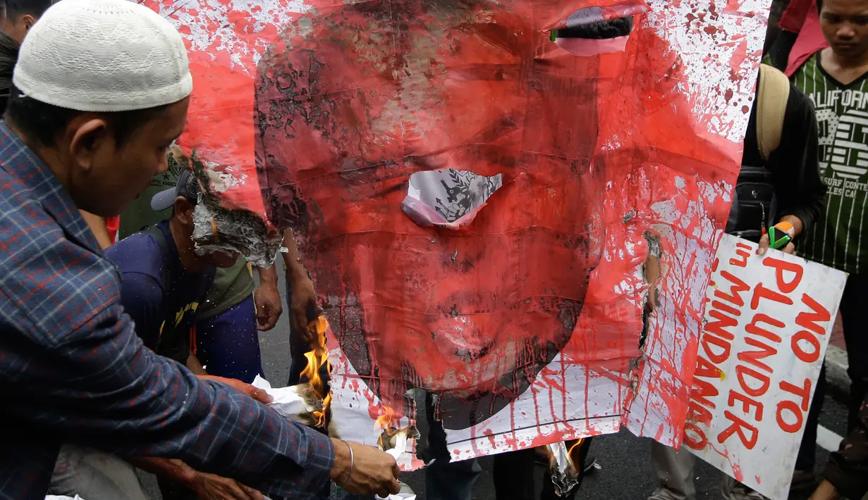 Pengunjuk rasa membakar poster Presiden AS, Donald Trump saat menggelar aksi di dekat Kedutaan Besar AS di Manila, Filipina (11/11). Mereka menolak kedatangan Presiden AS yang dijadwalkan tiba di Manila besok. (AP Photo/Aaron Favila)