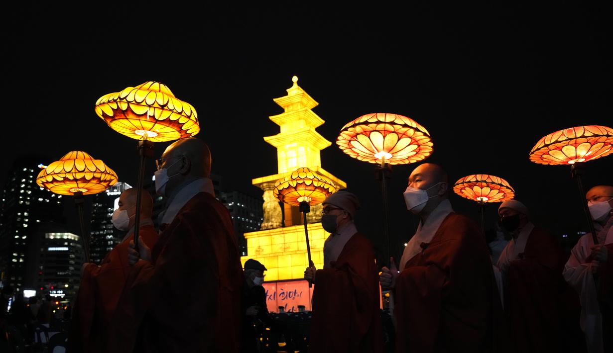 Biksu Buddha Korea Selatan mengenakan masker membawa lentera teratai berwarna-warni selama upacara pencahayaan untuk merayakan ulang tahun Buddha yang akan datang pada 8 Mei, di Seoul, Korea Selatan (5/4/2022). (AP Photo/Lee Jin-man)