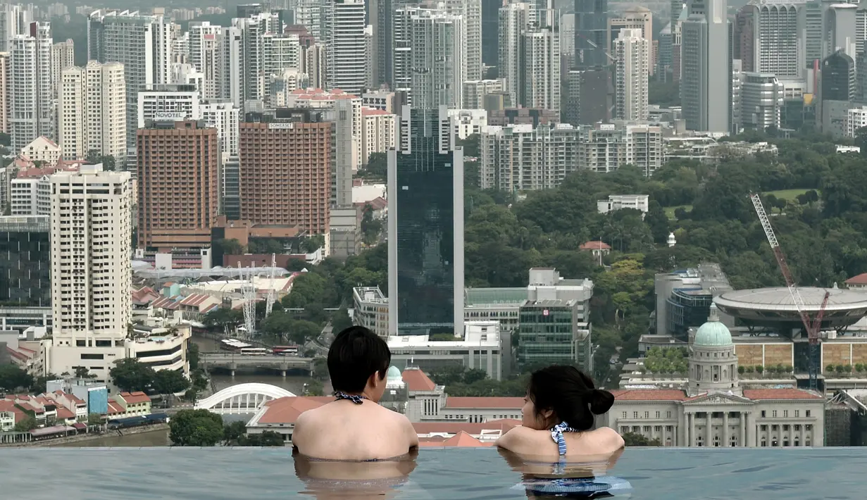 Wisatawan melihat pemandangan kota yang memukau dari kolam renang atap hotel Marina Bay Sands. Singapura dinobatkan sebagai kota paling mahal di dunia untuk tiga tahun berturut-turut di atas Zurich, Hong Kong, Jenewa dan Paris. (AFP PHOTO/Roslan RAHMAN)