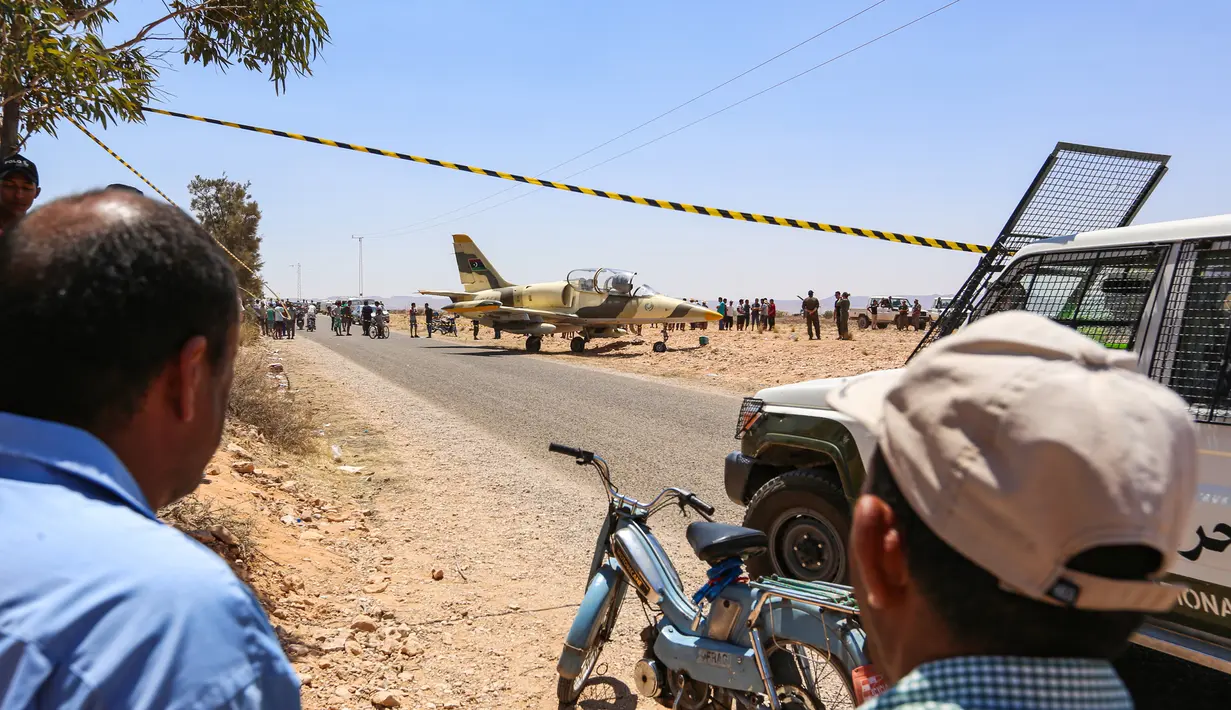 Warga melihat kondisi pesawat jet tempur Libya L-39 Albatros pasukan Khalifa Haftar di Kota Medenine di perbatasan Tunisia-Libya (22/7/2019). Pendaratan darurat jet tersebut sampai mengundang banyak perhatian warga di Kota Medenine. (AFP Photo/Fathi Nasri)