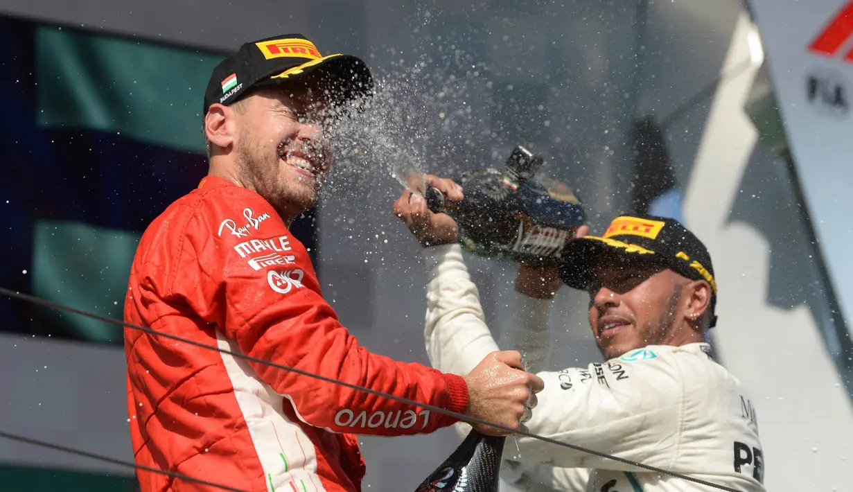 Pembalap Mercedes, Lewis Hamilton, menyemprotkan sampanye kearah pembalap Ferrari, Sebastian Vettel saat berselebrasi mejuarai GP Hungaria di Sirkuit Hungaroring, Mogyorod, (29/7). (Zoltan Balogh/MTI via AP)