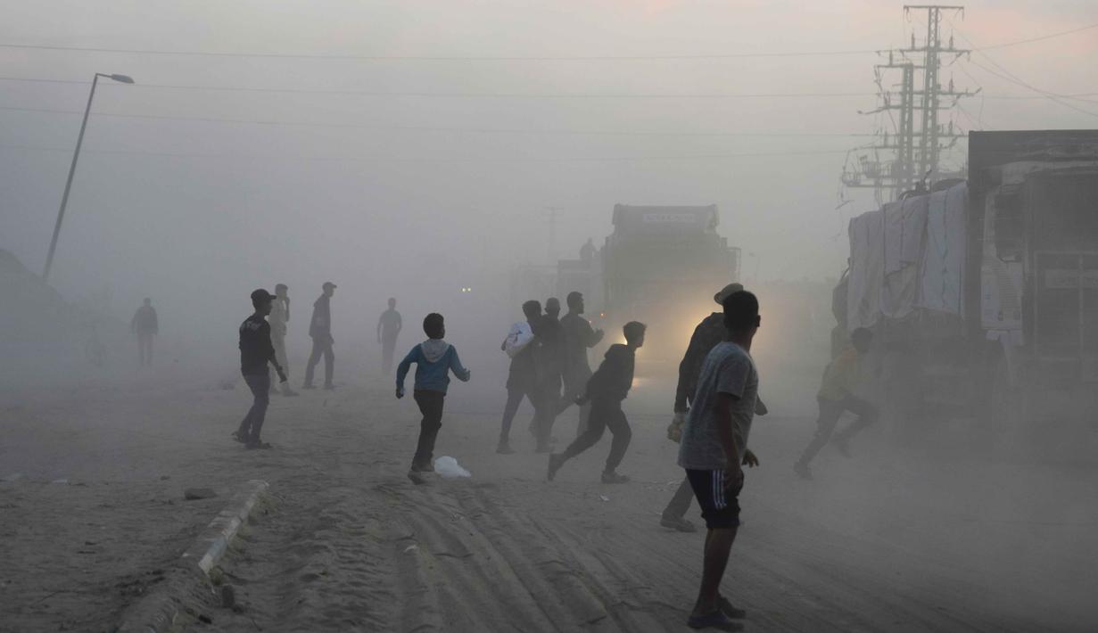 Meski demikian, sejak gencatan senjata dimulai pada 10 Oktober hingga 3 November 2025, PBB dan mitra-mitranya telah berhasil mengumpulkan lebih dari 37.000 ton bantuan dari pos-pos perlintasan Gaza. Tampak dalam foto, warga Palestina berbondong-bondong menuju truk yang mengangkut bantuan dari Program Pangan Dunia (WFP) saat truk-truk tersebut melintasi Deir al-Balah di Gaza Tengah, Sabtu, 8 November 2025.  (AP Photo/Abdel Kareem Hana)