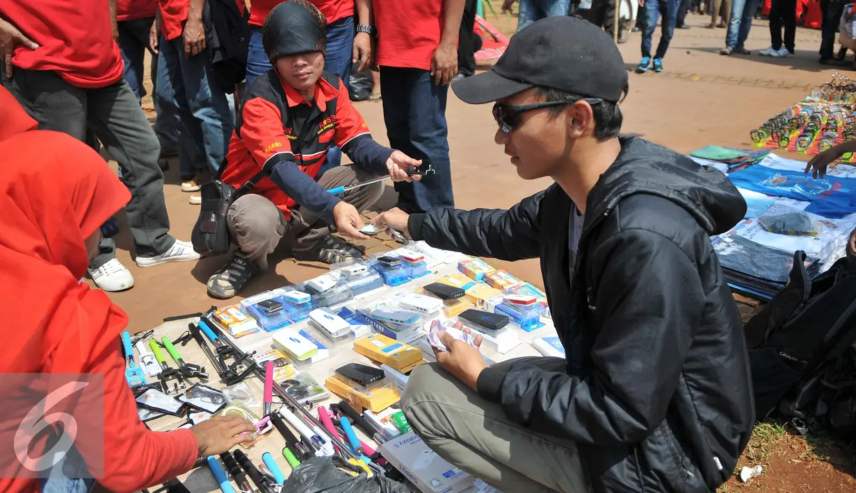 Buruh membeli tongsis saat demo memperingati hari lahirnya organisasi buruh internasional World Federation of Trade Unions (WFTU) di Jakarta (3/10/2015).  Sejumlah PKL memanfaatkan demo buruh untuk meraup sedikit keuntungan. (Liputan6.com/Gempur M Surya)