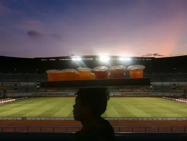 Seorang pedagang minuman melintas di tribun Stadion Utama Gelora Bandung Lautan Api (GBLA) menjelang laga pekan ketiga BRI Liga 1 2023/2024 antara Persib Bandung melawan Dewa United pada Jumat (14/07/2023). (Bola.com/Bagaskara Lazuardi)