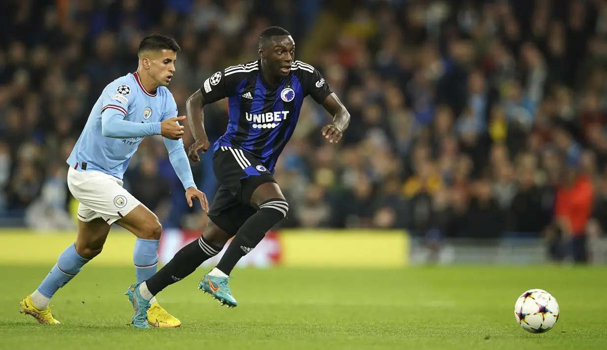 Bek Manchester City Joao Cancelo berebut bola dengan penyerang Copenhagen  Mohamed Daramy dalam matchday ketiga Grup G Liga Champions 2022/2023 di Etihad Stadium, Kamis (6/10/2022) dini hari WIB. Manchester City menang besar atas FC Copenhagen dengan skor telak 5-0. (AP Photo/Dave Thompson)