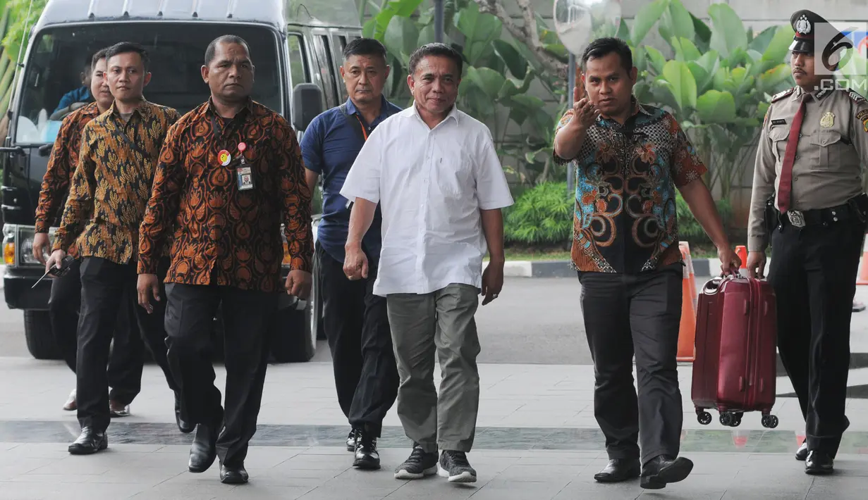 Gubernur Aceh Irwandi Yusuf dengan pengawalan petugas tiba di Gedung KPK, Jakarta, Rabu (4/7). Saat turun dari mobil tahanan, terlihat salah satu petugas KPK membawa satu koper berwarna merah tua. (Merdeka.com/Dwi Narwoko)