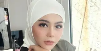 Jenita Janet tampil mengenakan kerudung putih dipadukan vest hijau dengan inner manset putihnya. Credit: Instagram (@jenitajanet)