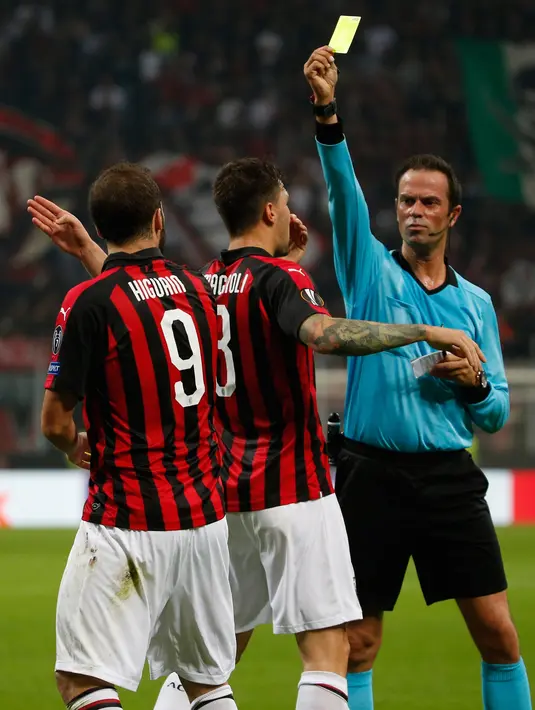 Wasit Bas Nijhuis memberikan kartu kuning kepada pemain AC Milan Gonzalo Higuain (kiri) saat bertanding melawan Real Betis dalam Grup F Liga Europa di Stadion San Siro, Milan, Italia, Kamis (25/10). AC Milan kalah 1-2. (AP Photo/Antonio Calanni)