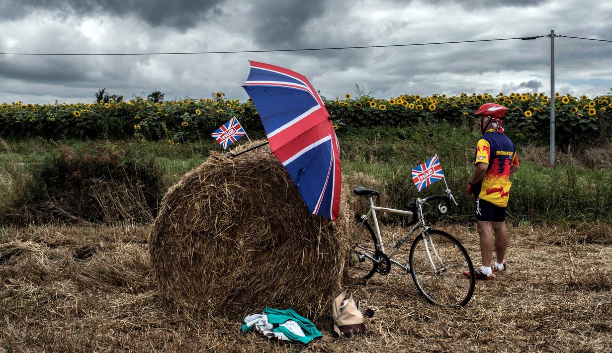 Seorang suporter menanti pebalap dengan membawa bendera Inggris Raya pada etape ke-11 dengan jarak tempuh 203,5 km antara Eymet and Pau, (12/7/2017). (AFP/Jeff Pachoud)
