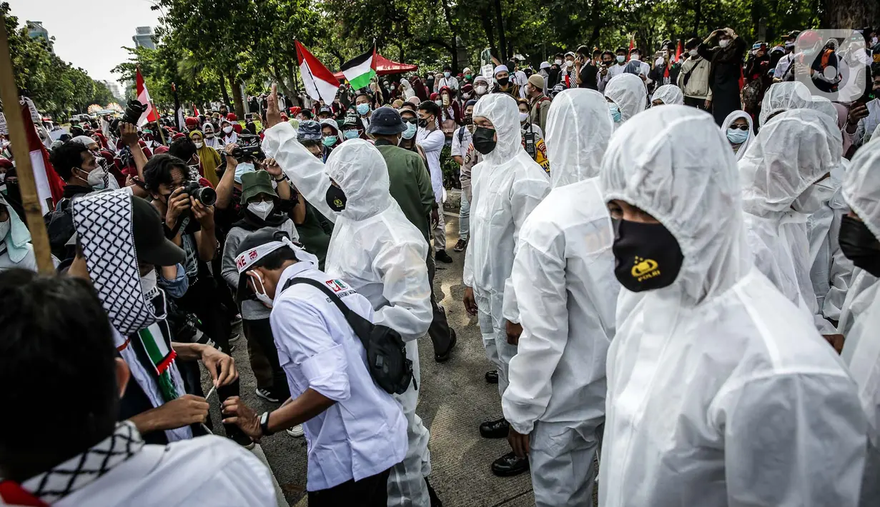 Petugas Satgas COVID-19 dari personel kepolisian menjaga protokol kesehatan peserta aksi solidaritas untuk Palestina di depan Kedutaan Besar Amerika Serikat, Jakarta, Selasa (18/5/2021). Massa mengutuk dan mengecam keras kekerasan yang dilakukan Israel atas Palestina. (Liputan6.com/Faizal Fanani)