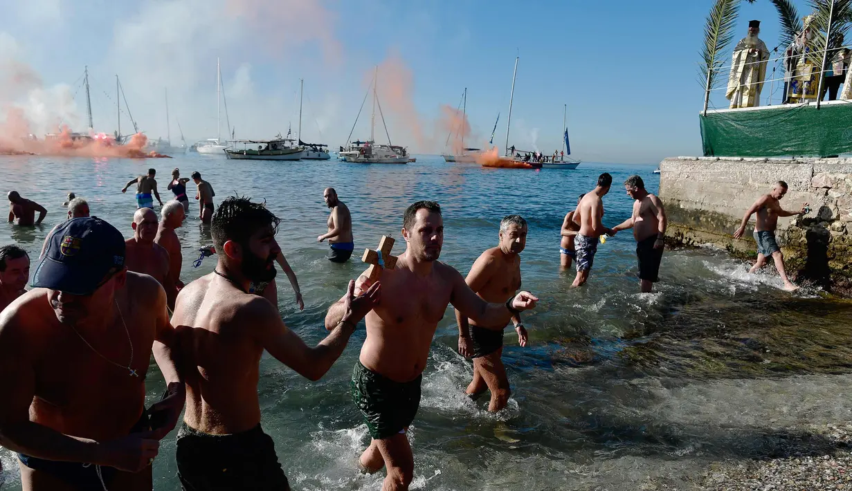 Angelos Filoxenidis memegang sebuah salib kayu setelah mengambilnya dari air dari pantai pinggiran pesisir Athena selama Hari Epiphany Orthodox, Yunani (6/1). (AFP Photo/Louisa Gouliamaki)